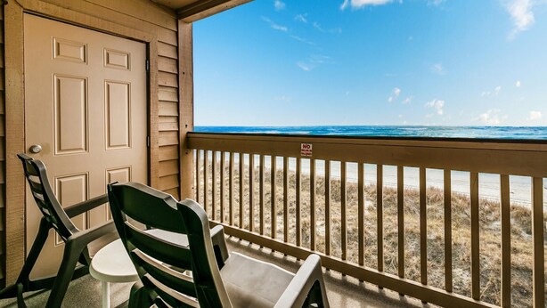 A room with a view of the beach, a door, and two chairs. - Renovated 1-bedroom, 1-bath 3rd floor oceanfront condo | Ocean Inn - 303 (North Myrtle Beach)