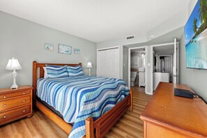 A bedroom with a bed, bedside tables, a desk, and a bathroom visible through an open door.