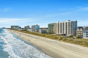 A beachfront hotel with multiple buildings, a sandy beach, and the ocean.