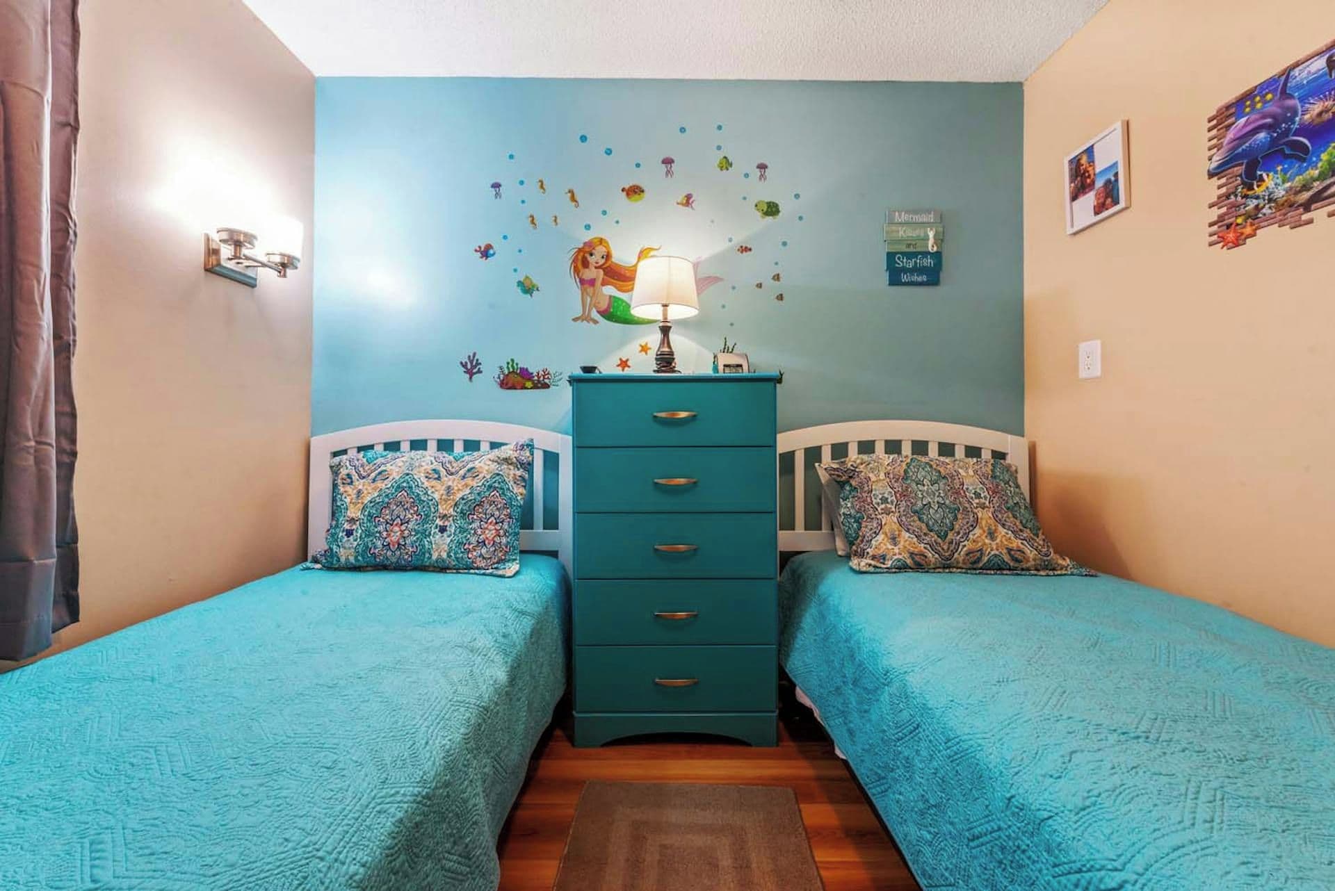 A bedroom with two single beds, a dresser, and a wall decorated with marine-themed stickers.