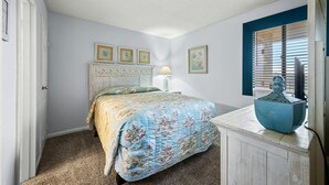 A bedroom with a bed, a dresser, and a window with blinds. - Calming paint palette and stylish design, 3-bedroom, 3-bath, sleeps 8, oceanfront condo | Summit -3D (North Myrtle Beach)