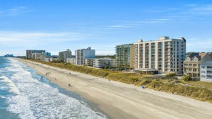 Un hôtel situé en bord de mer, composé de plusieurs bâtiments, avec une plage de sable et l’océan à proximité.