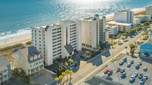 Un hôtel situé sur la côte, composé de plusieurs bâtiments, doté d’un parking et offrant une vue sur la plage.
