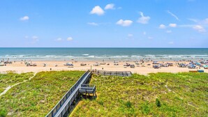 Une plage avec une promenade menant au bord de l’eau, une plage de sable et l’océan.