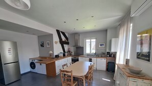 A modern kitchen with a central island, built-in appliances, and a dining area with wooden chairs. - Quiet, bright apartment, 400 metres from the town center, with parking lot (Aix-les-Bains)