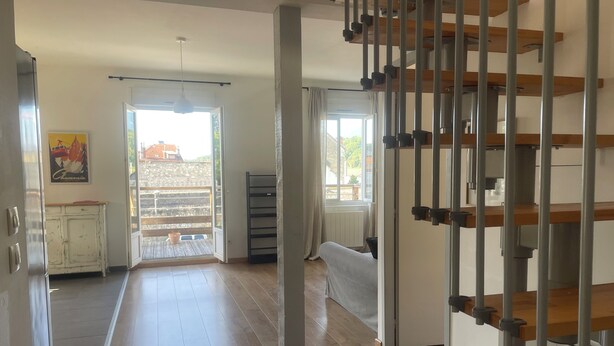A spacious room with a wooden floor, a staircase with metal railings, a white cabinet, and a window with curtains. - Quiet, bright apartment, 400 metres from the town center, with parking lot (Aix-les-Bains)