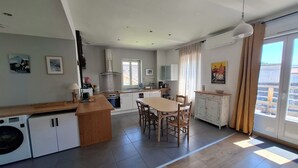 A modern kitchen with a dining area, a washing machine, and a large window with curtains. - Quiet, bright apartment, 400 metres from the town center, with parking lot (Aix-les-Bains)
