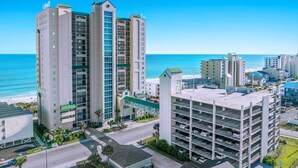 Ein Hochhaus-Hotel mit mehreren Stockwerken, einer Tiefgarage und Blick auf den Strand.