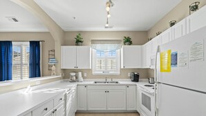 A modern kitchen with white cabinets, a built-in oven, and a refrigerator with a freezer. - Golf Course Views, 2-bed, 2-bath Condo, Barefoot Resort | Ironwood - 834 (North Myrtle Beach)