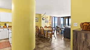 A bright yellow interior with a dining area, kitchen, and a view of the sea. - 3-bedroom, 2-bathroom, oceanfront condo, Plenty of updates and upgrades | Sea Castle - 5C (North Myrtle Beach)