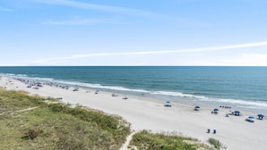A beach with a wide sandy area, a clear sky, and the ocean in the background. - 3-bedroom, 2-bathroom, oceanfront condo, Plenty of updates and upgrades | Sea Castle - 5C (North Myrtle Beach)