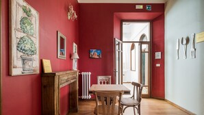 Un coin repas avec une table et des chaises en bois, une cheminée et des murs rouges.