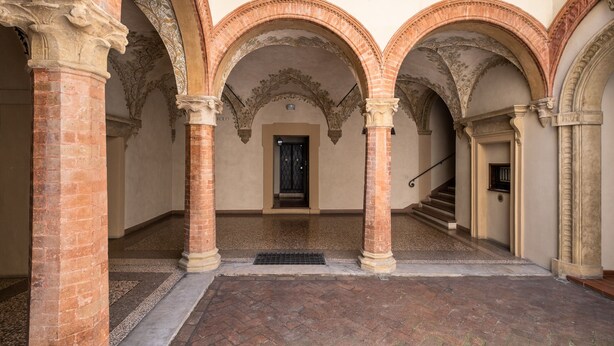 Une cour intérieure dotée de trois arcades et d’un escalier menant à un niveau supérieur.