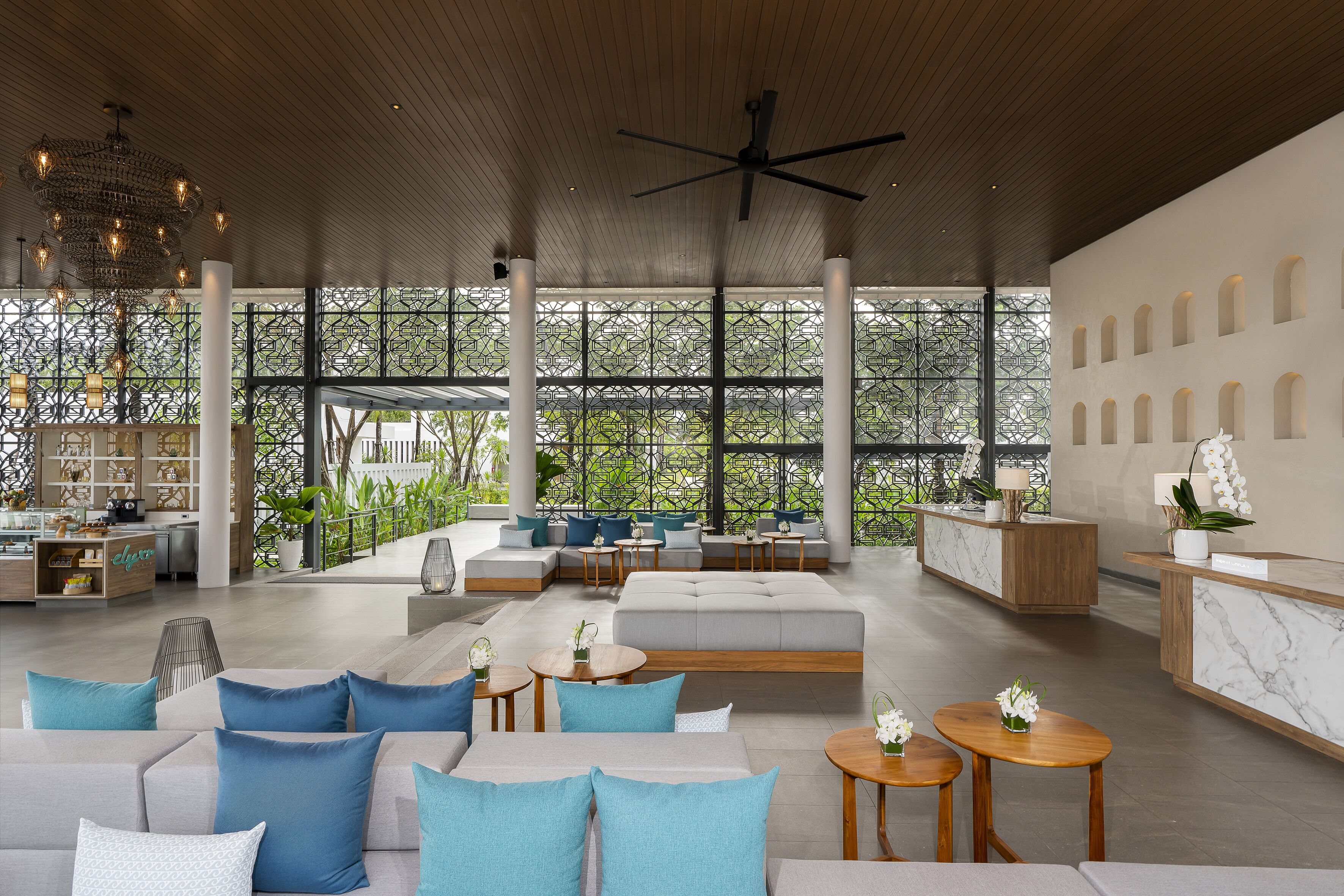 Un lobby espacioso con techo alto, una mesa de recepción, zonas de estar y amplias ventanas que ofrecen vistas a zonas verdes.