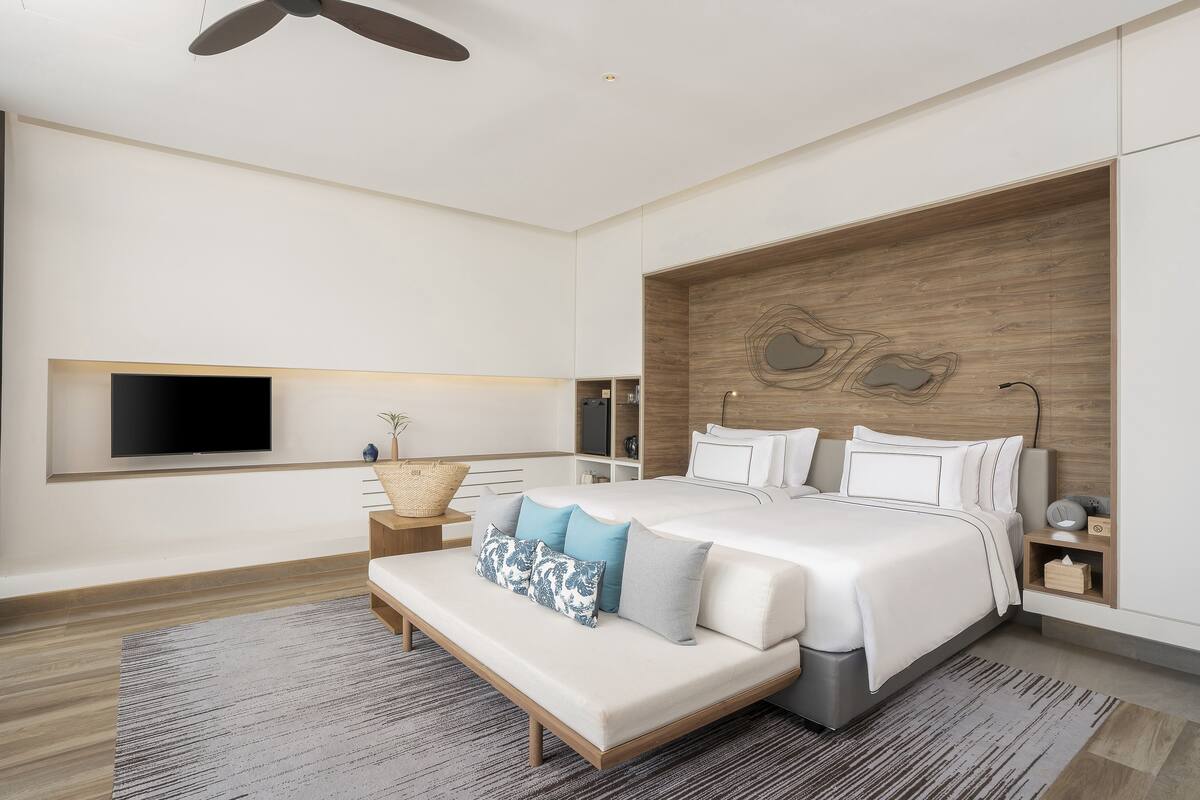 Quarto moderno com uma cama grande, uma televisão de tela plana na parede e uma parede de destaque em madeira.