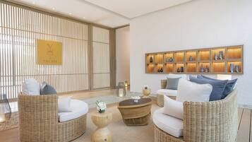 A modern lounge area with wicker furniture, a wall-mounted display of vases, and a sliding door with vertical blinds.