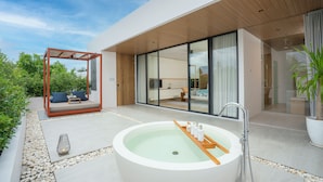 A modern outdoor spa area with a large hot tub, a wooden swing chair, and a glass-enclosed living space. - Melia Phuket Mai Khao (Mai Khao)