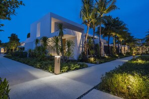 A modern building with a clean, geometric design, surrounded by lush greenery and palm trees.