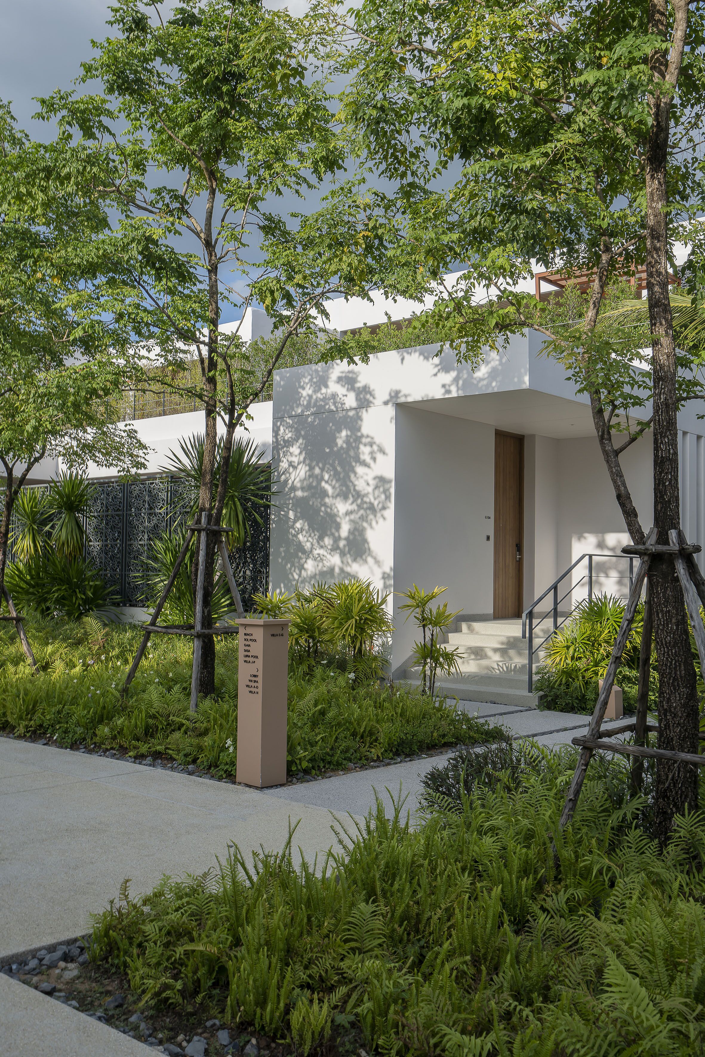 A modern building with a minimalist design, featuring a concrete pathway leading to a wooden door.