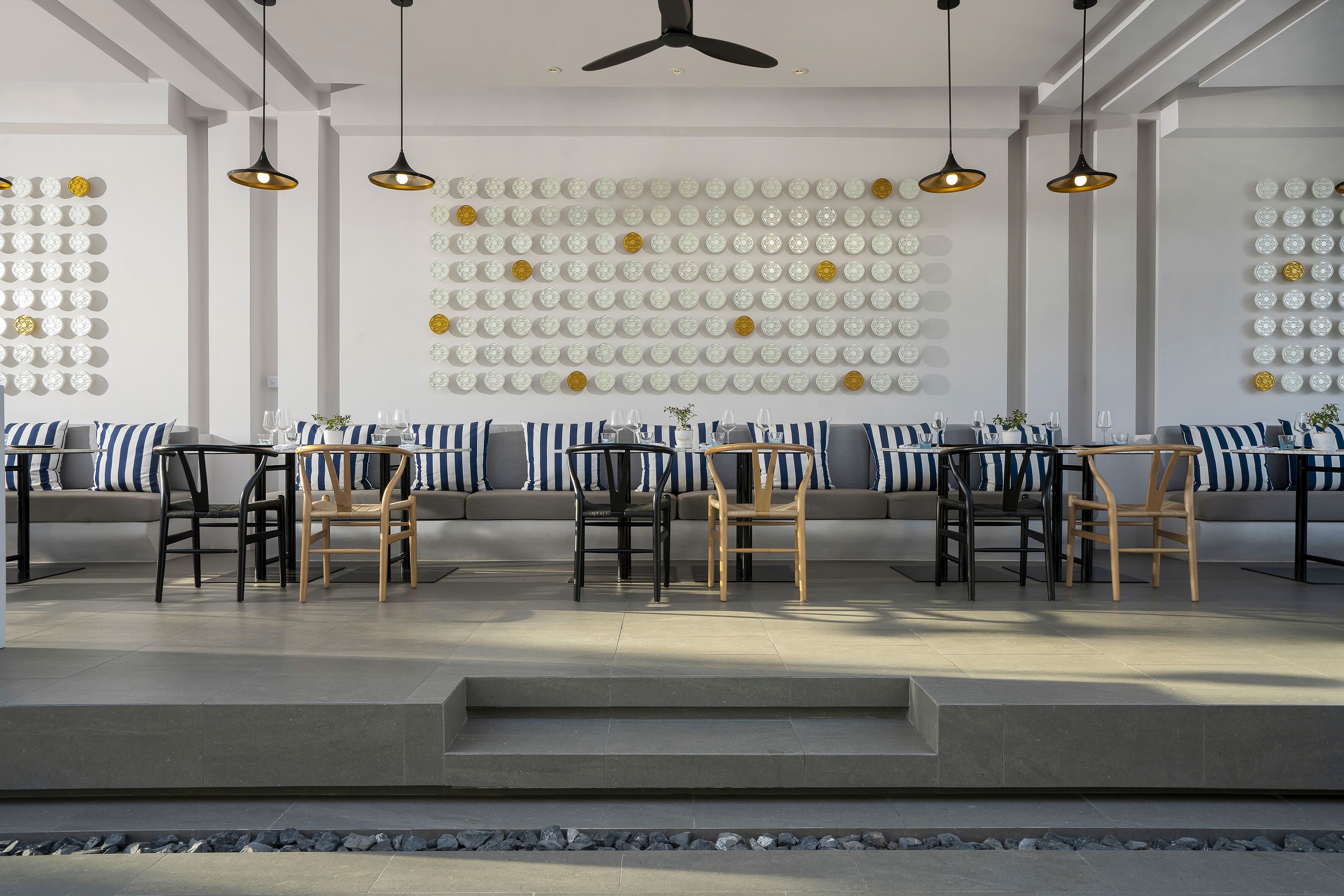 A modern dining area with a long table, chairs, and a wall decorated with plates.