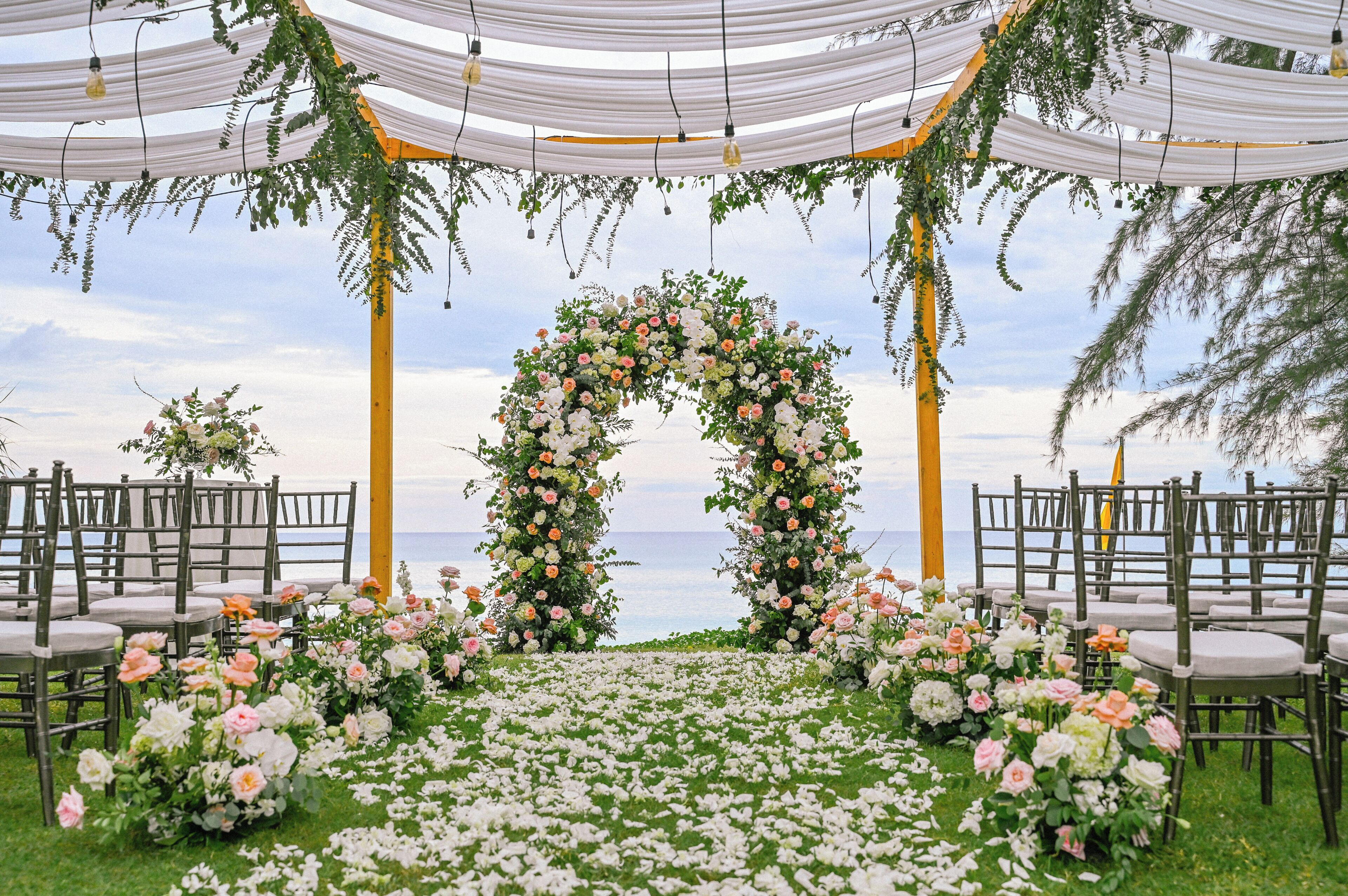 An outdoor wedding setup with a floral arch and chairs arranged for guests.