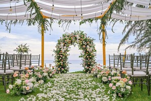 An outdoor wedding setup with a floral arch and chairs arranged for guests.