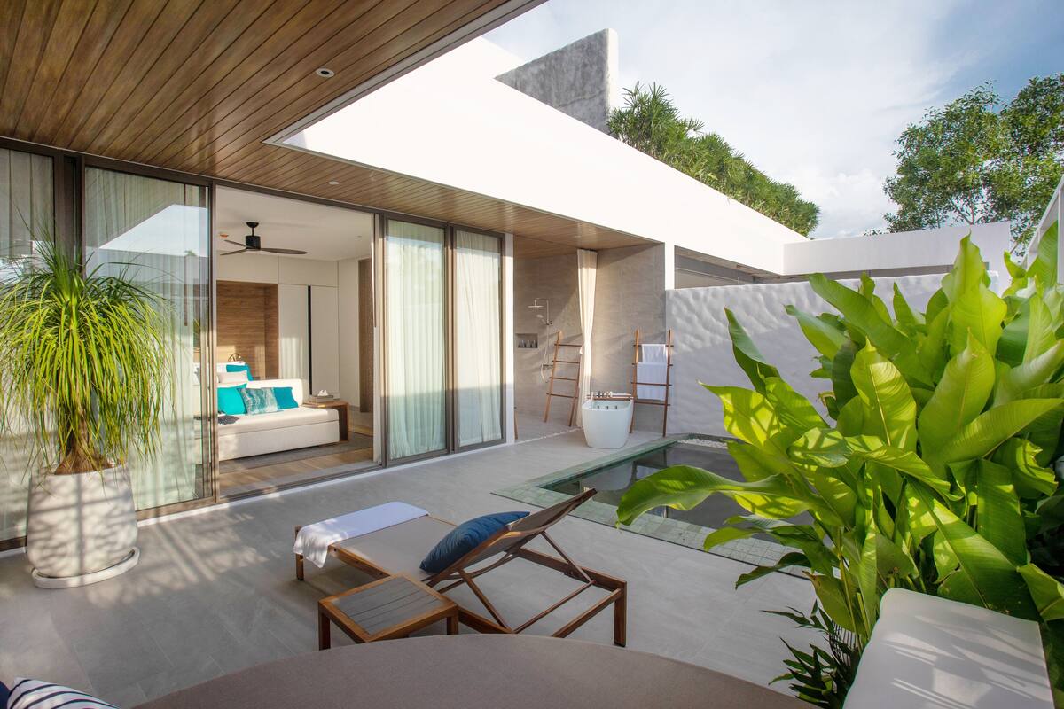 Uma área externa moderna com piscina, espreguiçadeiras e um terraço envidraçado.