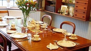 A dining table set for a meal with chairs around it. - Oak End Lodge (Sevenoaks)