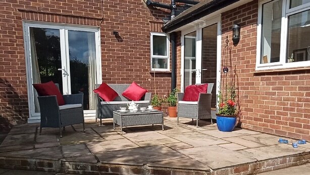 A patio with outdoor furniture, a table set with tea, and potted plants. - Oak End Lodge (Sevenoaks)