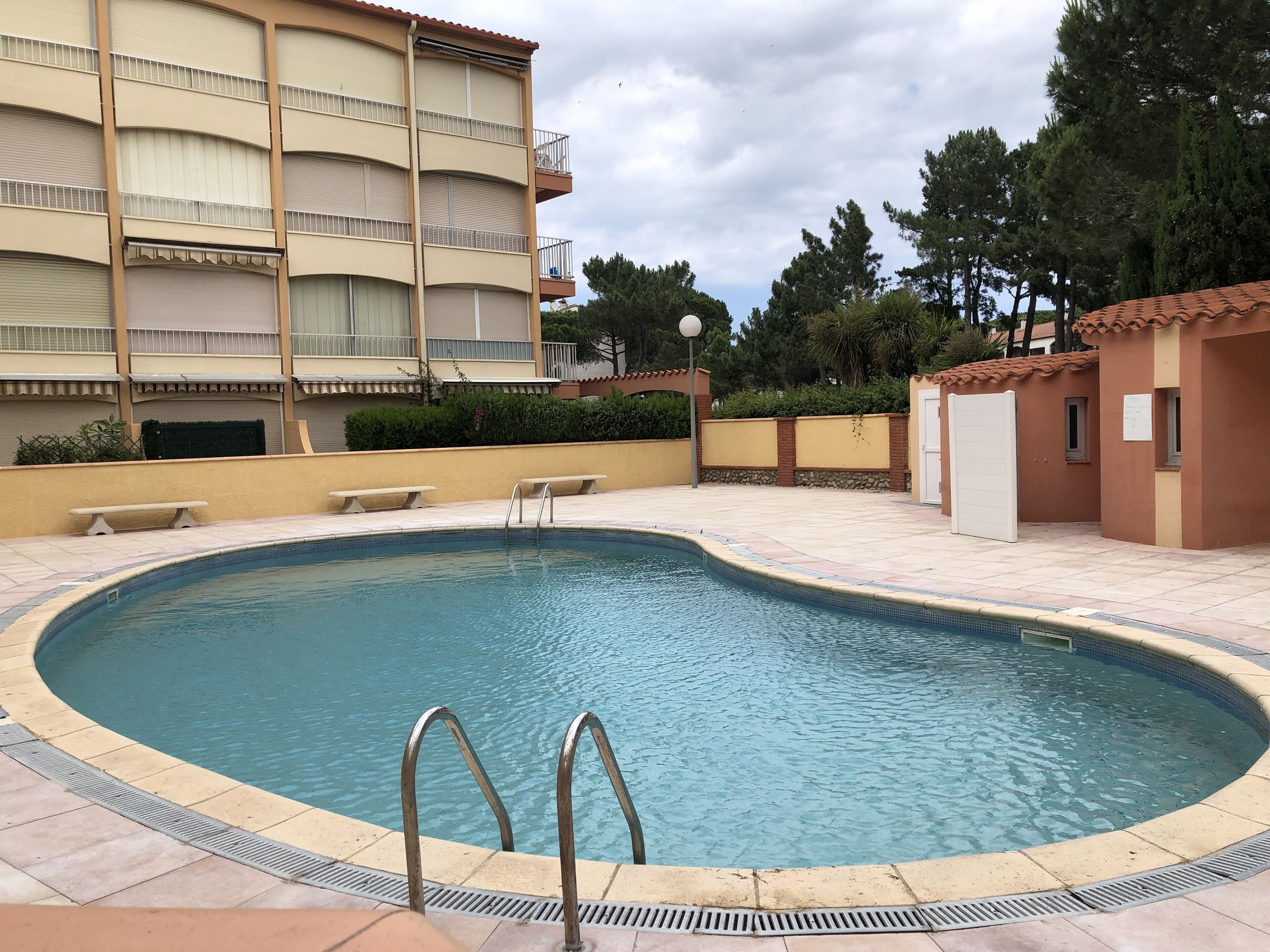 A swimming pool with metal ladders, surrounded by a tiled deck.