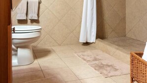 Un baño con inodoro, ducha con cortina, toallero y toalla colgada en la pared.