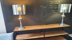 Una habitación con dos lámparas sobre una estantería de madera, una pizarra con escritura y una silla blanca.