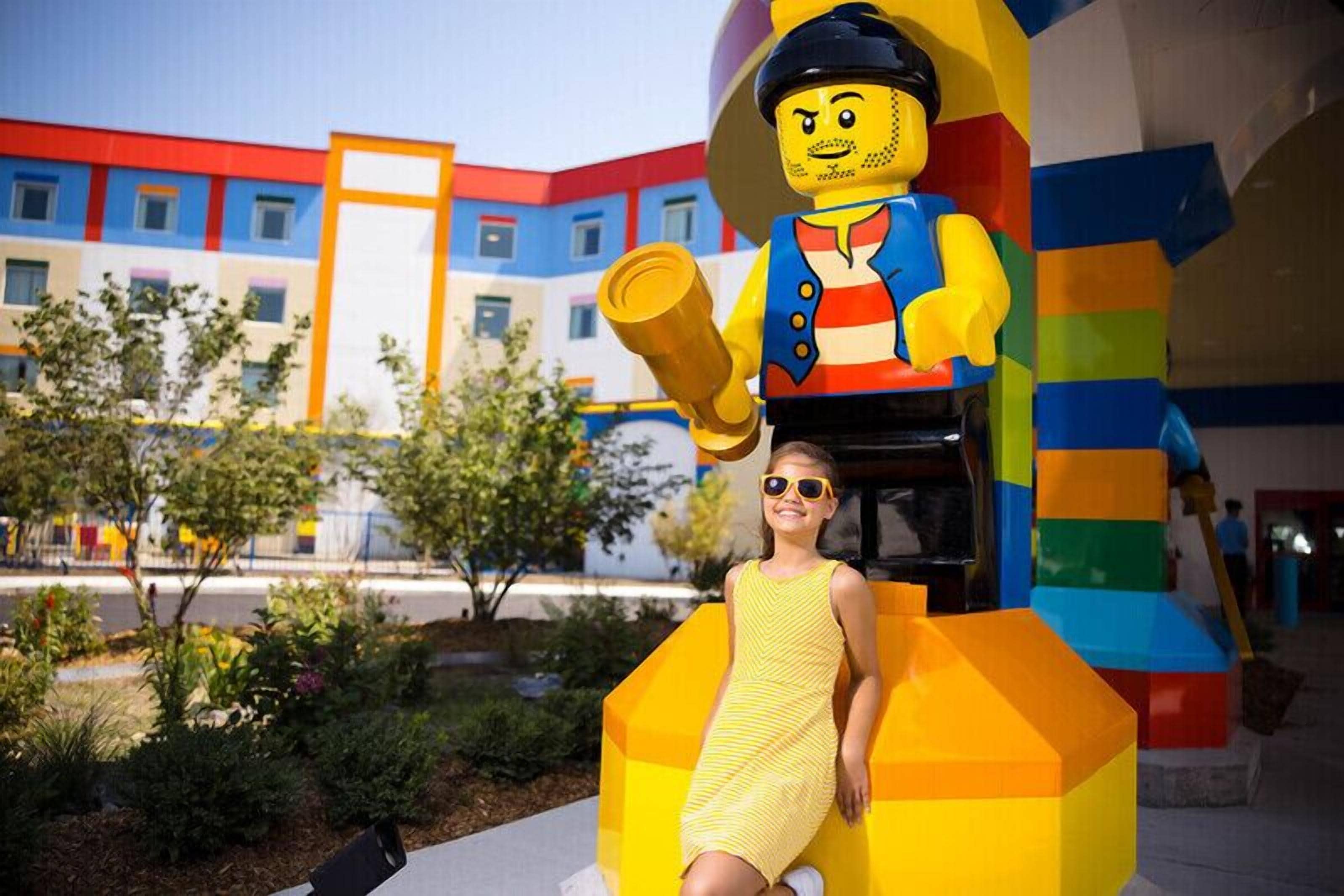 A person sitting on a colorful, geometric structure outdoors with a building in the background.