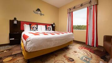 A hotel room with a large bed, a headboard with skull and crossbones decorations, a nightstand, and a window with red and white curtains.