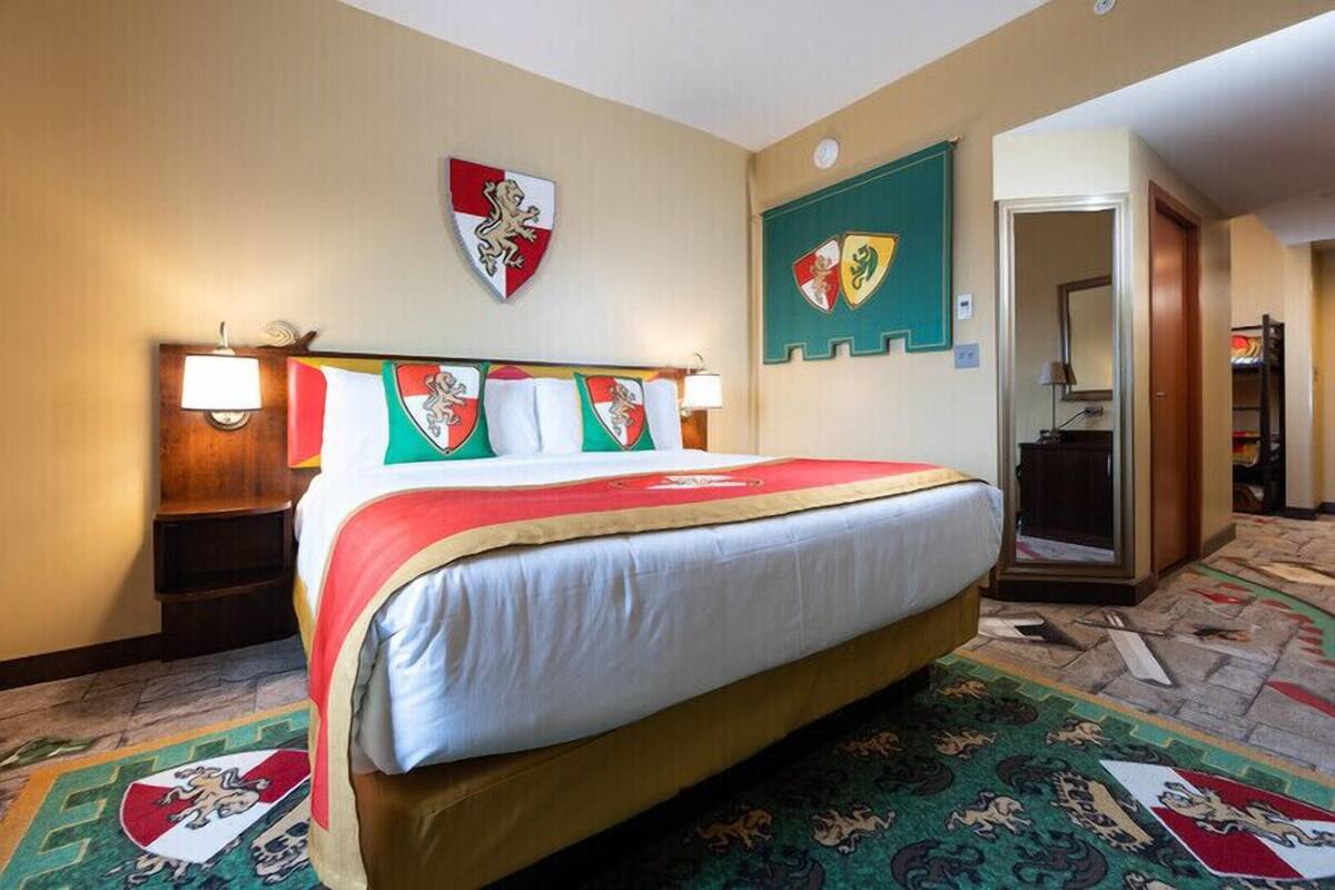A hotel room with a bed, a coat of arms on the wall, and a door leading to a bathroom.