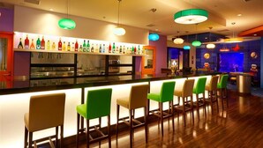 Zona de bar con una barra larga, varias luces colgantes y una variedad de botellas.