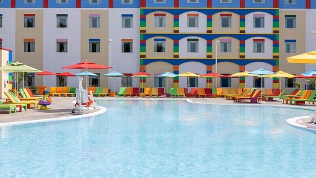 Una piscina con sombrillas de colores y sillas de descanso.