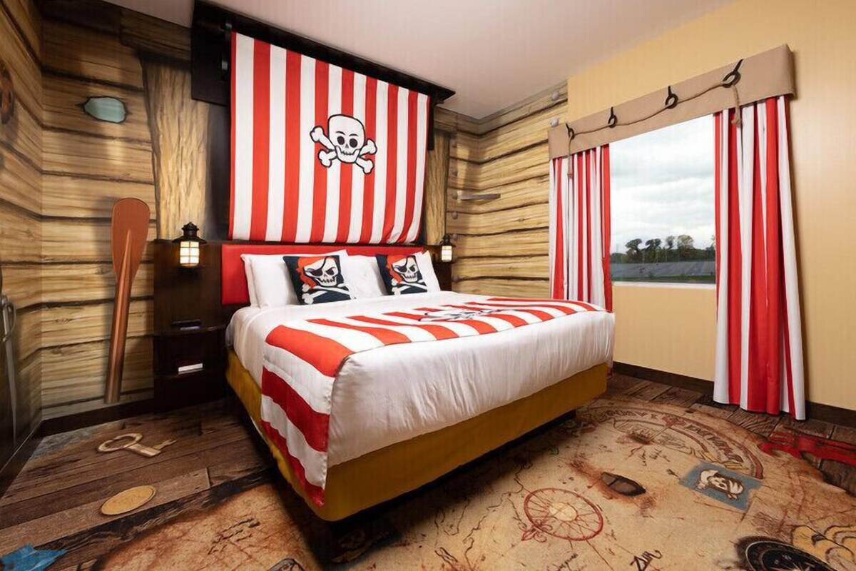 A pirate-themed room with a bed, striped curtains, and nautical decor.