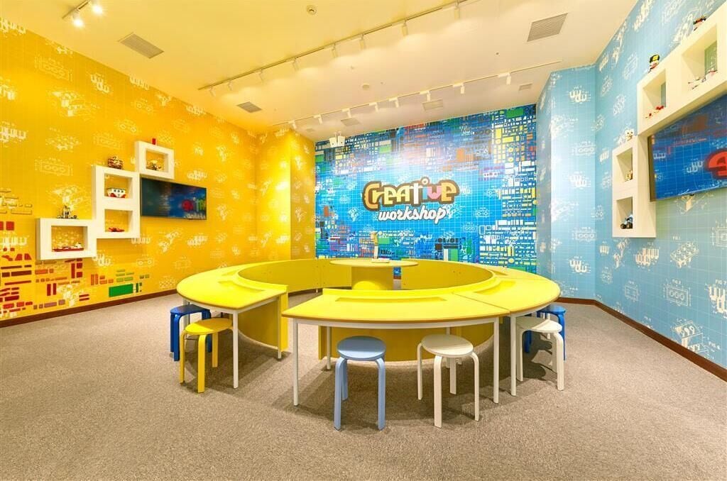 Una habitación de colores brillantes con una mesa amarilla en el centro y taburetes, rodeada de paredes con un estampado azul y amarillo.