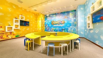 Una habitación de colores brillantes con una mesa amarilla en el centro y taburetes, rodeada de paredes con un estampado azul y amarillo.