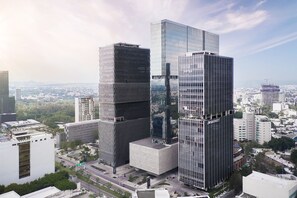 Um edifício moderno e imponente, com um design retorcido singular, rodeado por outros arranha-céus e um ambiente urbano movimentado.