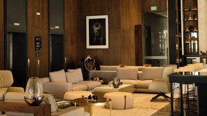 Un hall d’hôtel moderne avec un plafond en bois, des fauteuils confortables, une table basse et un coin bar.