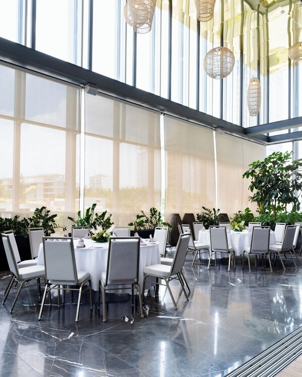 A spacious conference room with large windows, modern chandeliers, and a polished marble floor.
