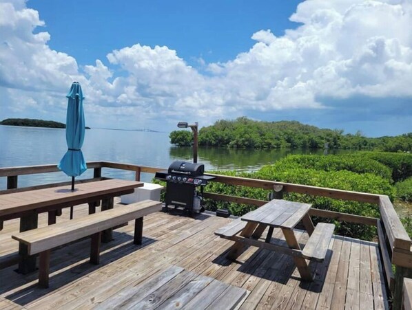 Enjoy al fresco dining with a barbecue grill and picnic tables overlooking the serene water and lush surroundings.