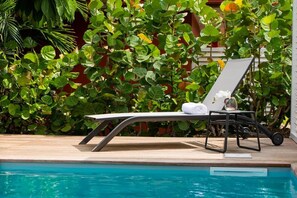 A poolside lounge chair with a towel and a small table with a flower vase. - Tropic Lagoon loft, by the lagoon ! (Le François)