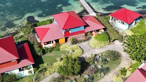 An aerial view of a coastal property with multiple buildings, a dock extending into clear blue waters, and a boat visible in the distance. - Tropic Lagoon loft, by the lagoon ! (Le François)