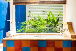A bathroom with a tiled floor, a window with a view of green plants, and a white towel on the counter. - Tropic Lagoon loft, by the lagoon ! (Le François)