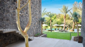 A stone building with a staircase, a pool area with umbrellas, and palm trees. - Huayacán Cuernavaca Curamoria Collection (Jiutepec)