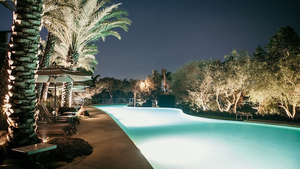 A swimming pool with lounge chairs and umbrellas, surrounded by palm trees and a night sky. - Huayacán Cuernavaca Curamoria Collection (Jiutepec)