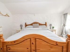 Ein Schlafzimmer mit einem hölzernen Bett, weißen Wänden und einer weißen Decke.